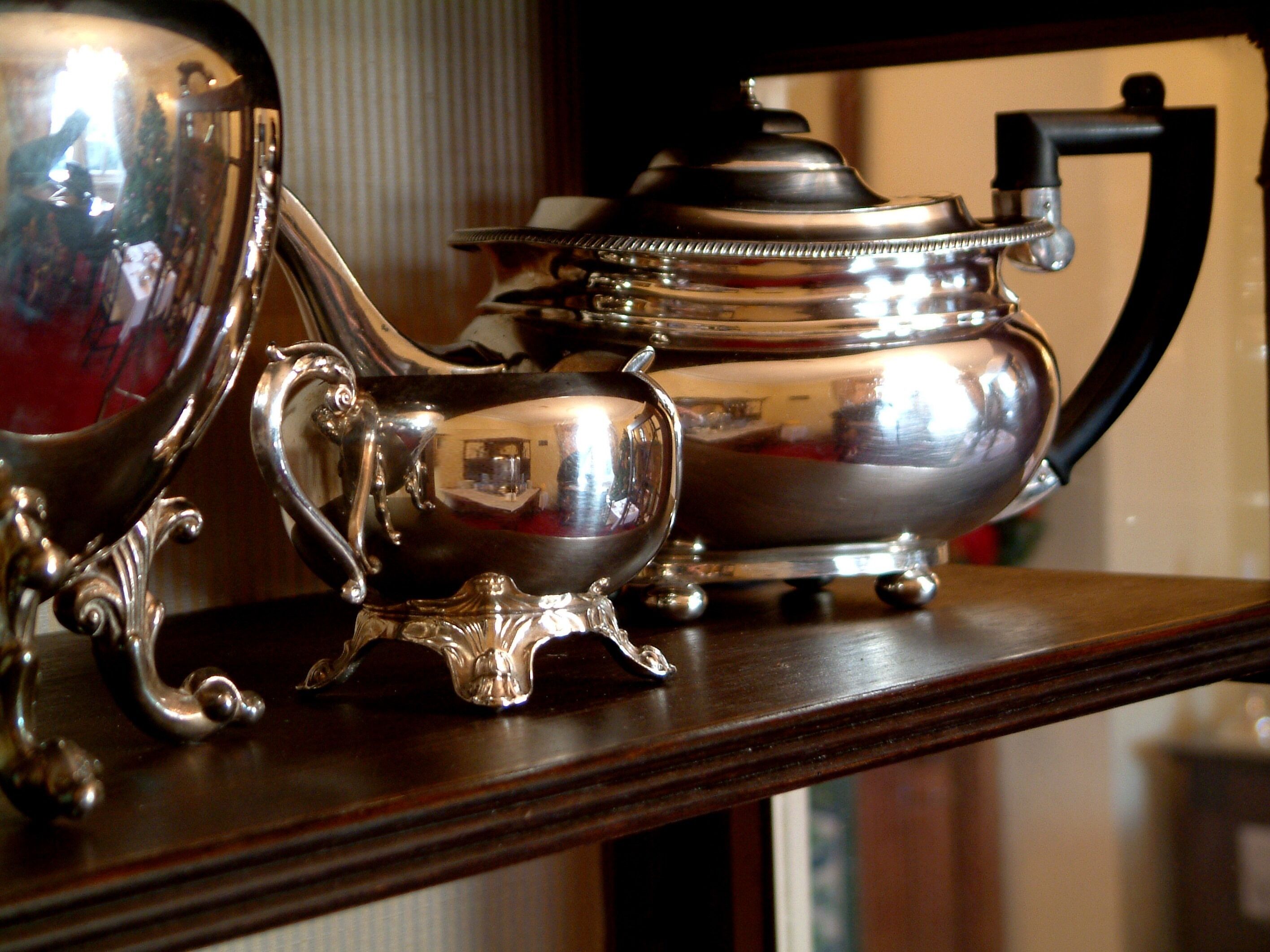 A silver tea set with a teapot and cups on a wooden surface.
