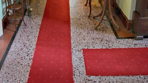 A hallway with a red carpet, ornate furniture, and a chandelier. - Innisfree House (Dundalk)