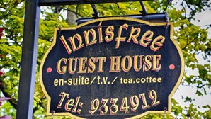 A sign for 'Indisfree Guest House' with contact information and services listed.