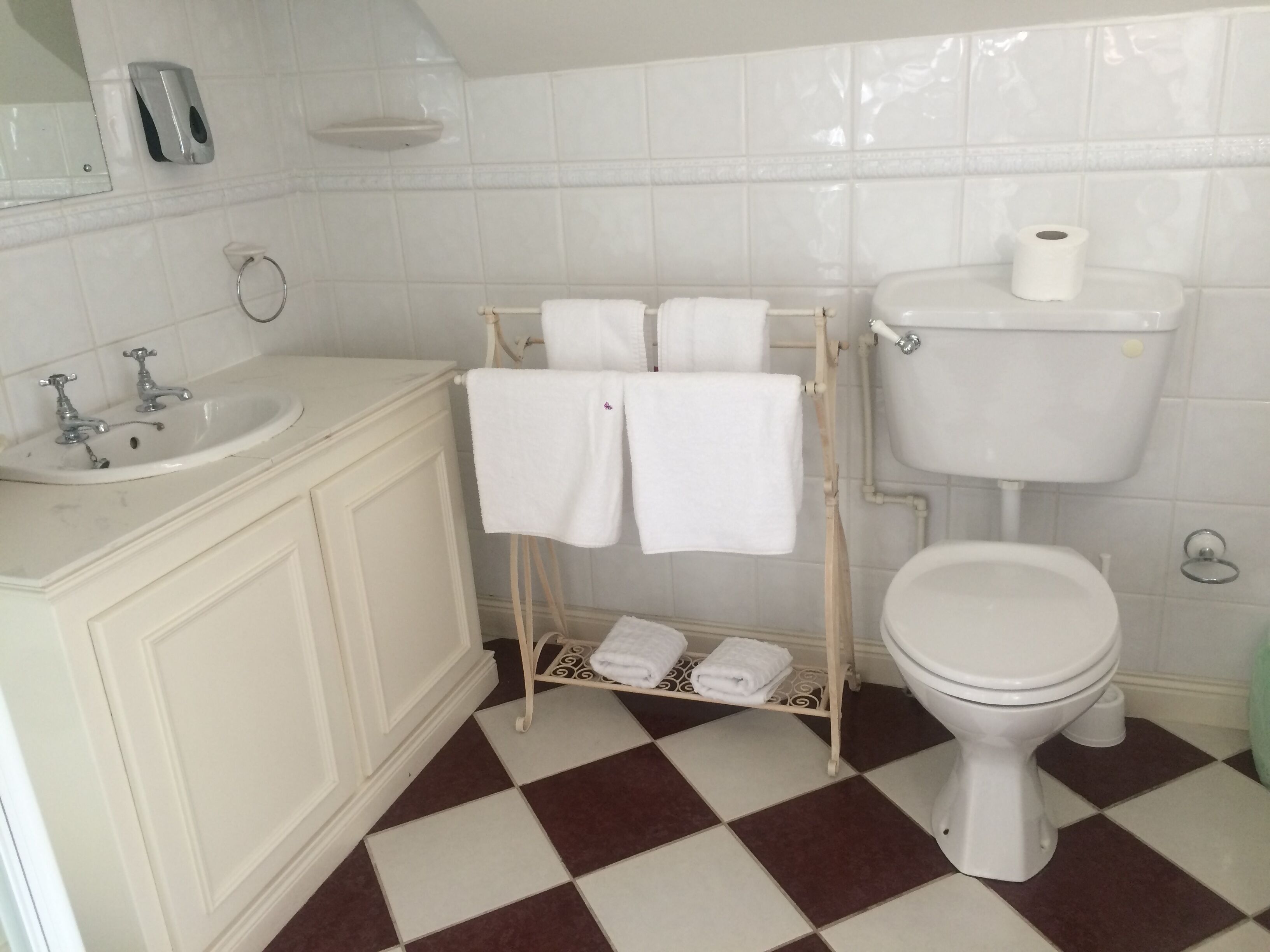 Un baño con lavamanos blanco, inodoro y toallero con toallas.