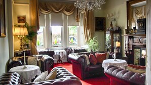 A traditional room with leather sofas, a chandelier, and a fireplace. - Innisfree House (Dundalk)