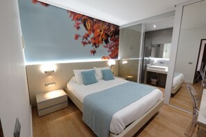 A modern bedroom with a large bed, bedside tables, a mirror, and a wall-mounted light fixture. - Hotel Vila da Guarda (A Guarda)