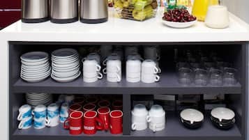 Una colazione a buffet con macchine da caffè, frutta e bevande.
