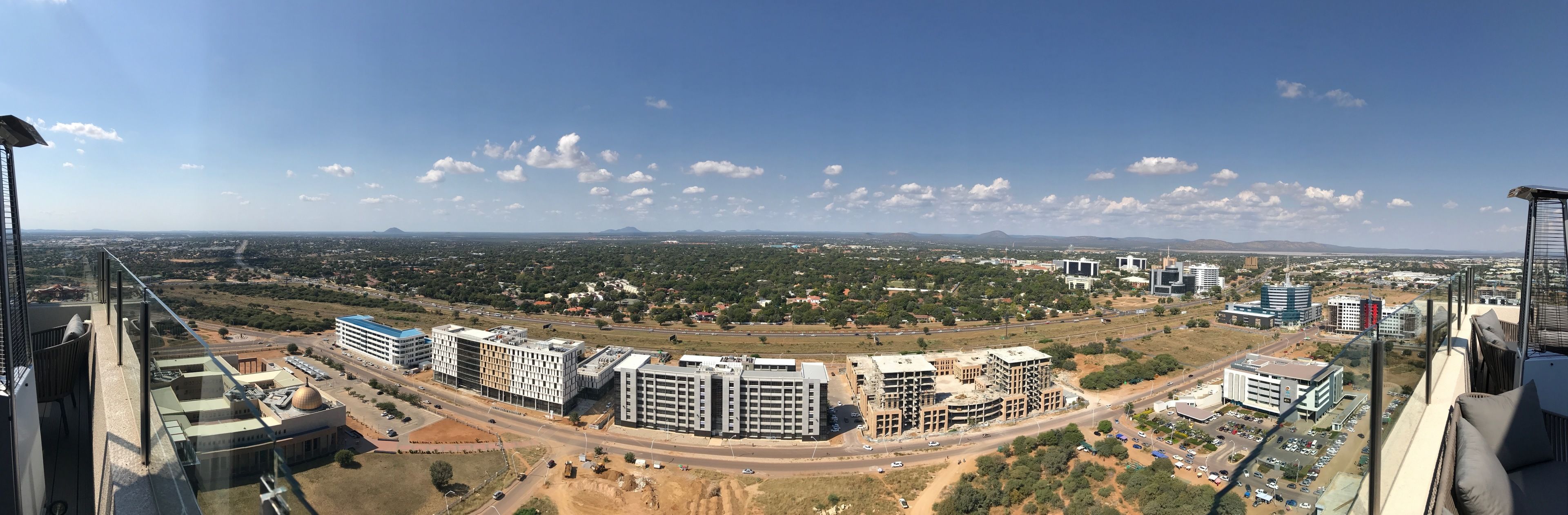 A high-rise building with a view of a cityscape, including roads, buildings, and distant mountains.