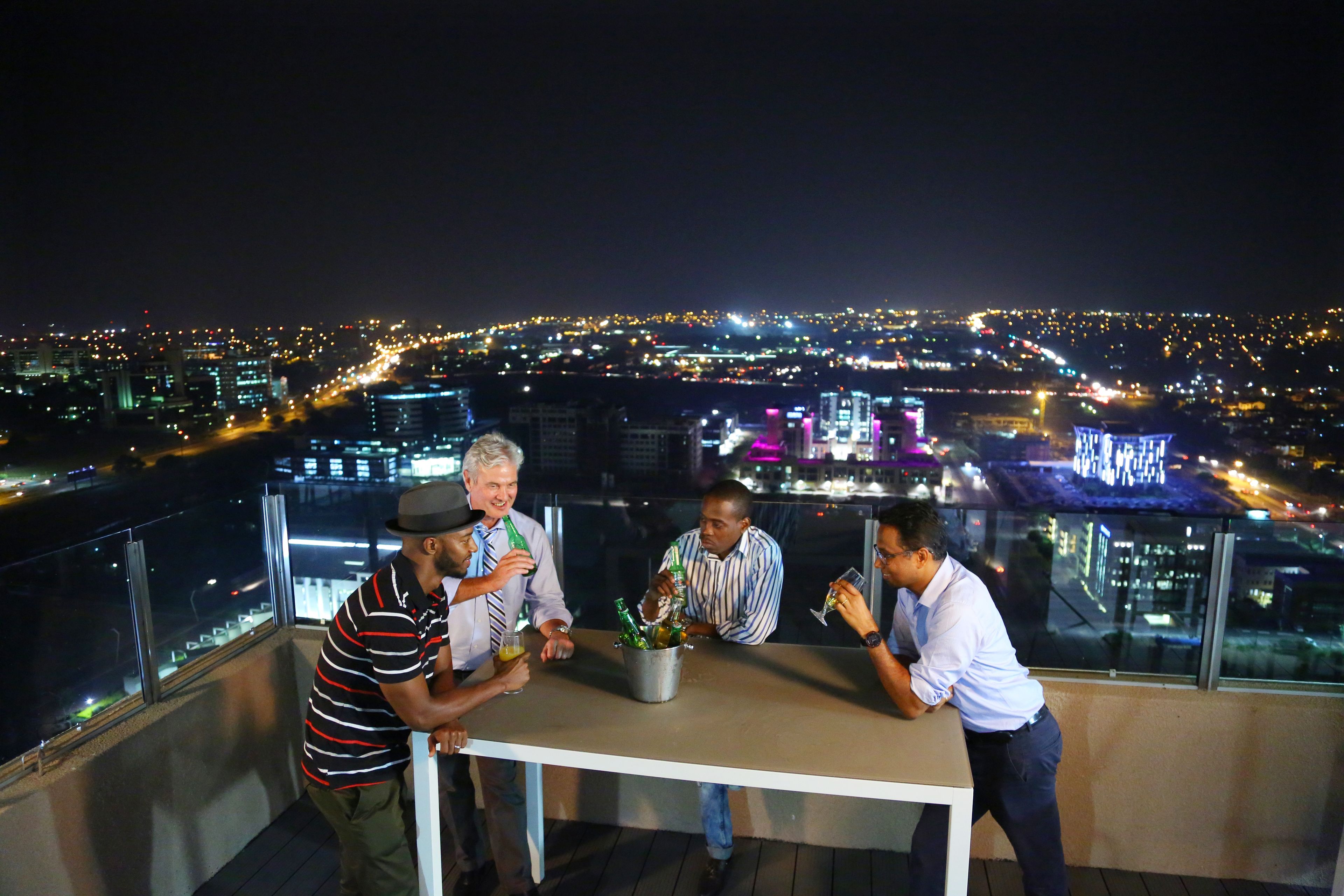 A group of people on a balcony overlooking a cityscape at night.