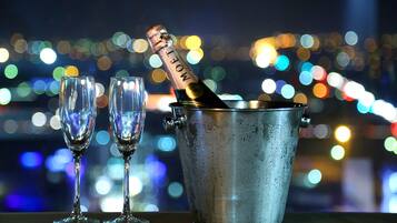 A bottle of champagne in a metal bucket with two empty glasses beside it.