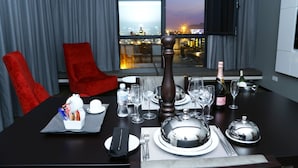 A dining table set for two with a view of the city at dusk.