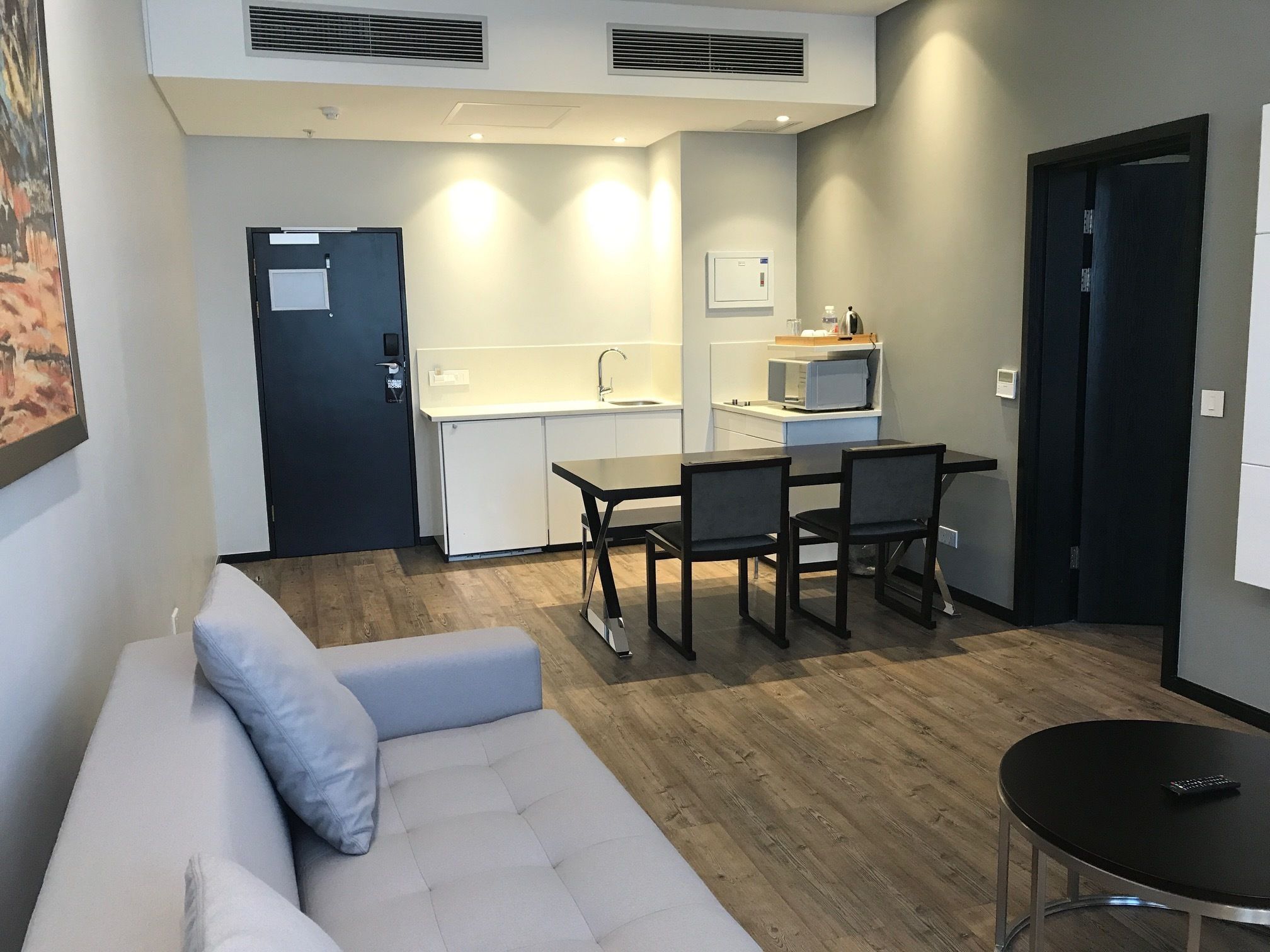 A compact living space with a kitchenette, a dining area, and a seating area with a sofa and a small table.