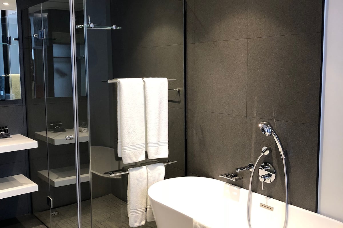 A modern bathroom with a freestanding bathtub, a glass-enclosed shower, and a vanity with shelves.