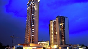 A high-rise hotel with multiple floors and balconies, a construction crane in the foreground, and a clear sky.