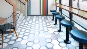 A modern interior with a staircase, hexagonal patterned floor, and a seating area with blue stools. - The Hotel Salem (Salem)