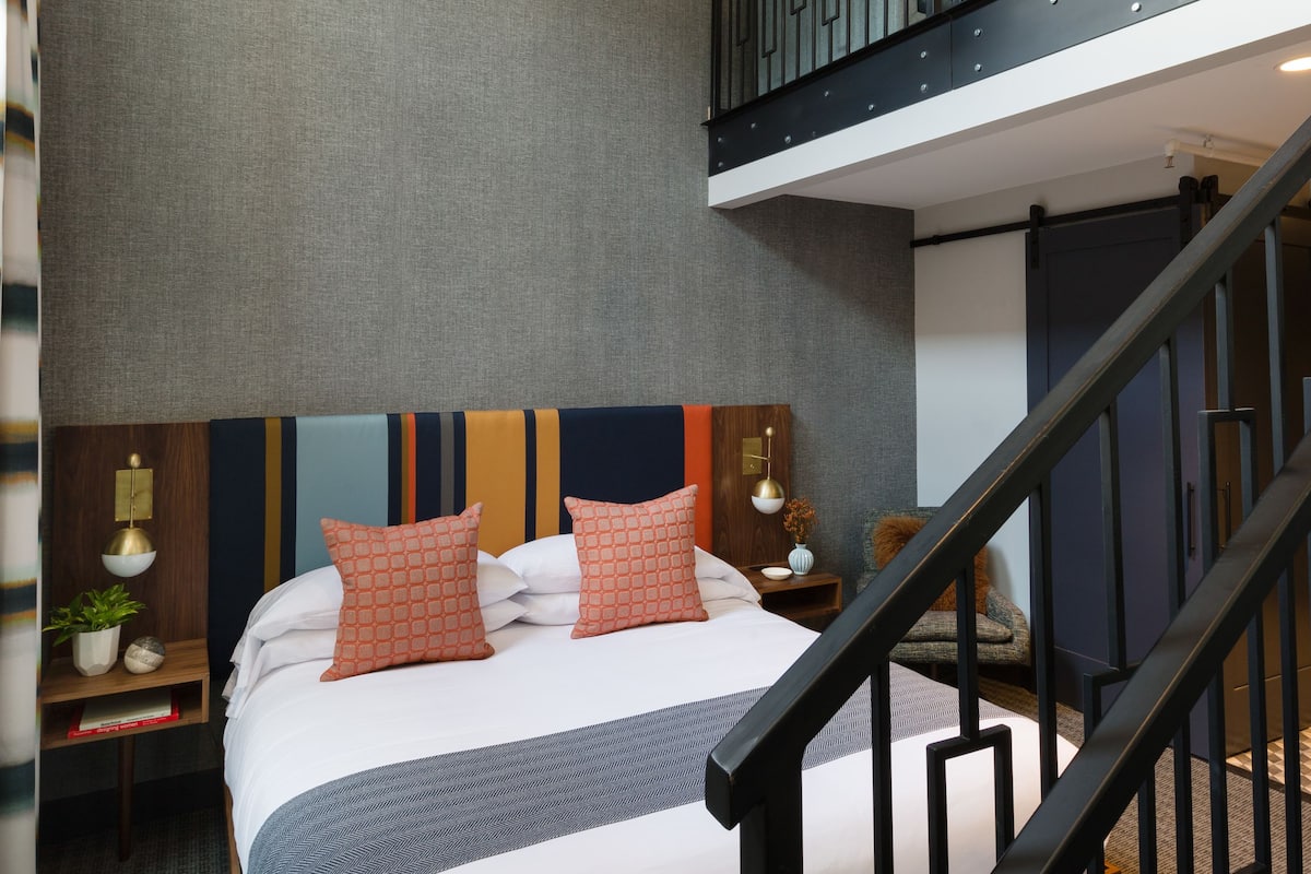 Une chambre d’hôtel moderne dotée d’un grand lit, d’un balcon et d’un escalier.