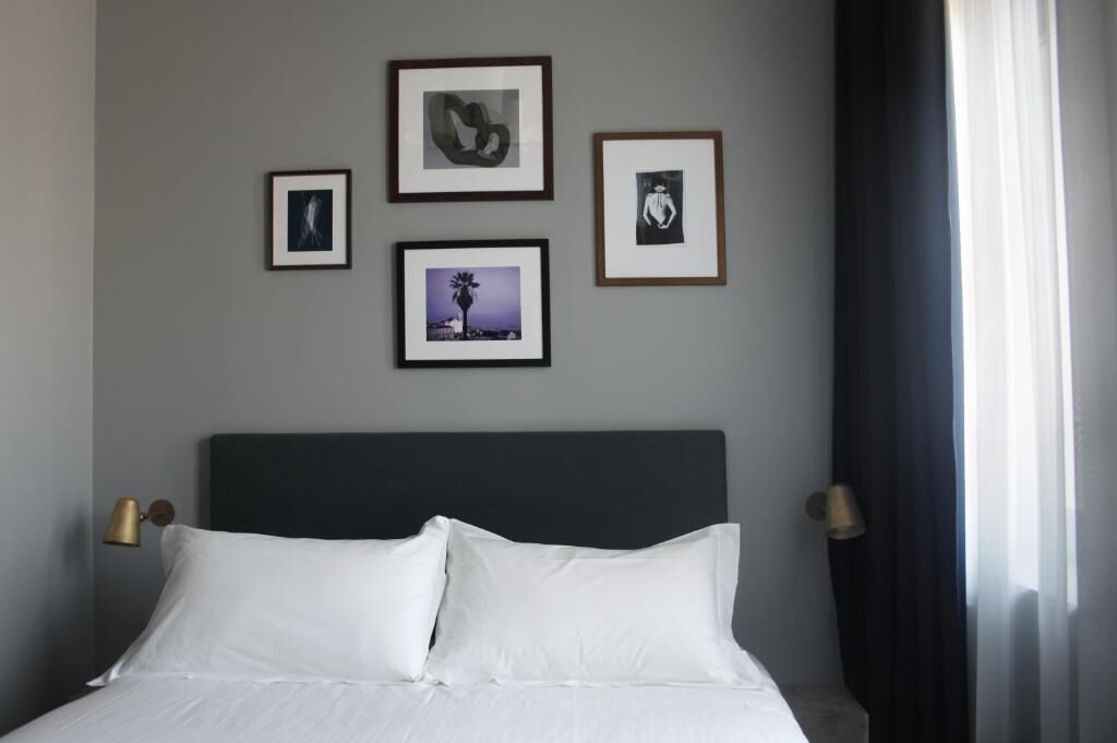A hotel room with a bed, framed pictures on the wall, and two bedside lamps.