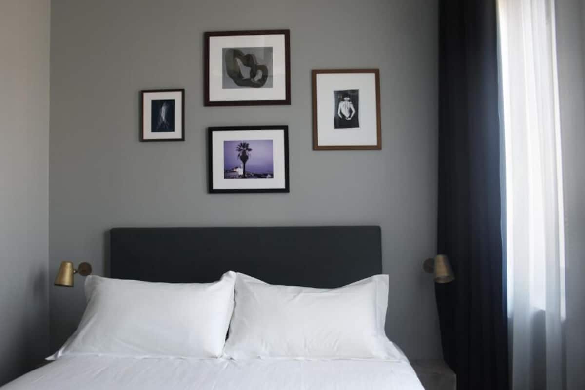 Ein Hotelzimmer mit einem Bett, gerahmten Bildern an der Wand und zwei Nachttischlampen.