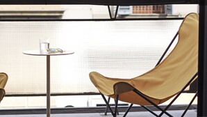 A balcony with a yellow chair, a small round table, and a glass of water. - c-hotels Joy (Florence)