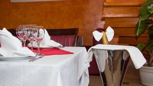 A dining table set with wine glasses, plates, and cutlery, a red napkin, and a champagne flute with a white napkin. - Cypa Hotel (Abidjan)
