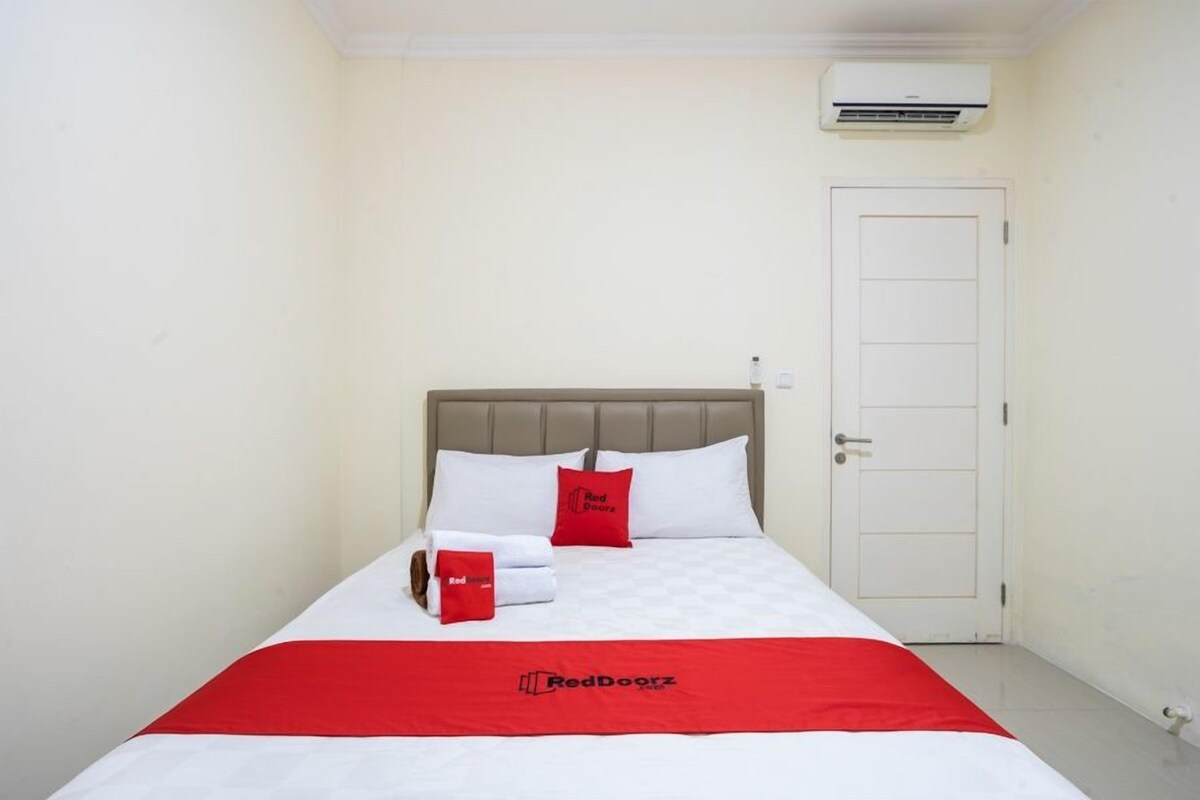 Une chambre d’hôtel avec un lit, une porte et un appareil de climatisation fixé au mur.