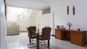 A modern kitchen with a dining area, a staircase, and wooden cabinets. - RedDoorz Plus near Siloam Karawaci (Curug)