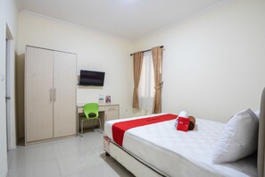 A hotel room with a bed, a desk, a chair, a wardrobe, and a TV on the wall.