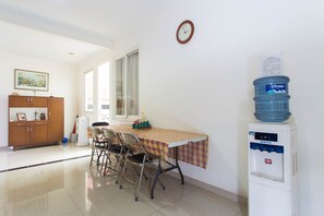 A dining area with a table, chairs, a water dispenser, and a clock on the wall.