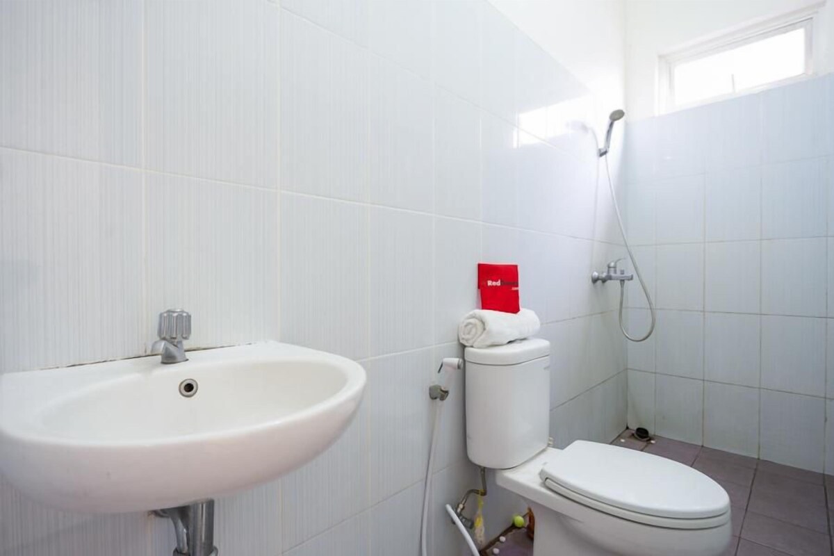 Une salle de bain avec un lavabo, des toilettes et une douche, le tout de couleur blanche.