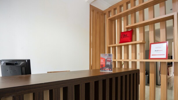 A reception desk with a wooden panel design, a RedDoor's logo, and a framed partnership certificate. - RedDoorz Plus near Siloam Karawaci (Curug)