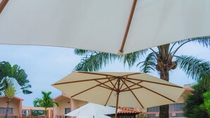 A poolside area with lounge chairs, umbrellas, and a pool. - Hotel Elais (Pointe-Noire)