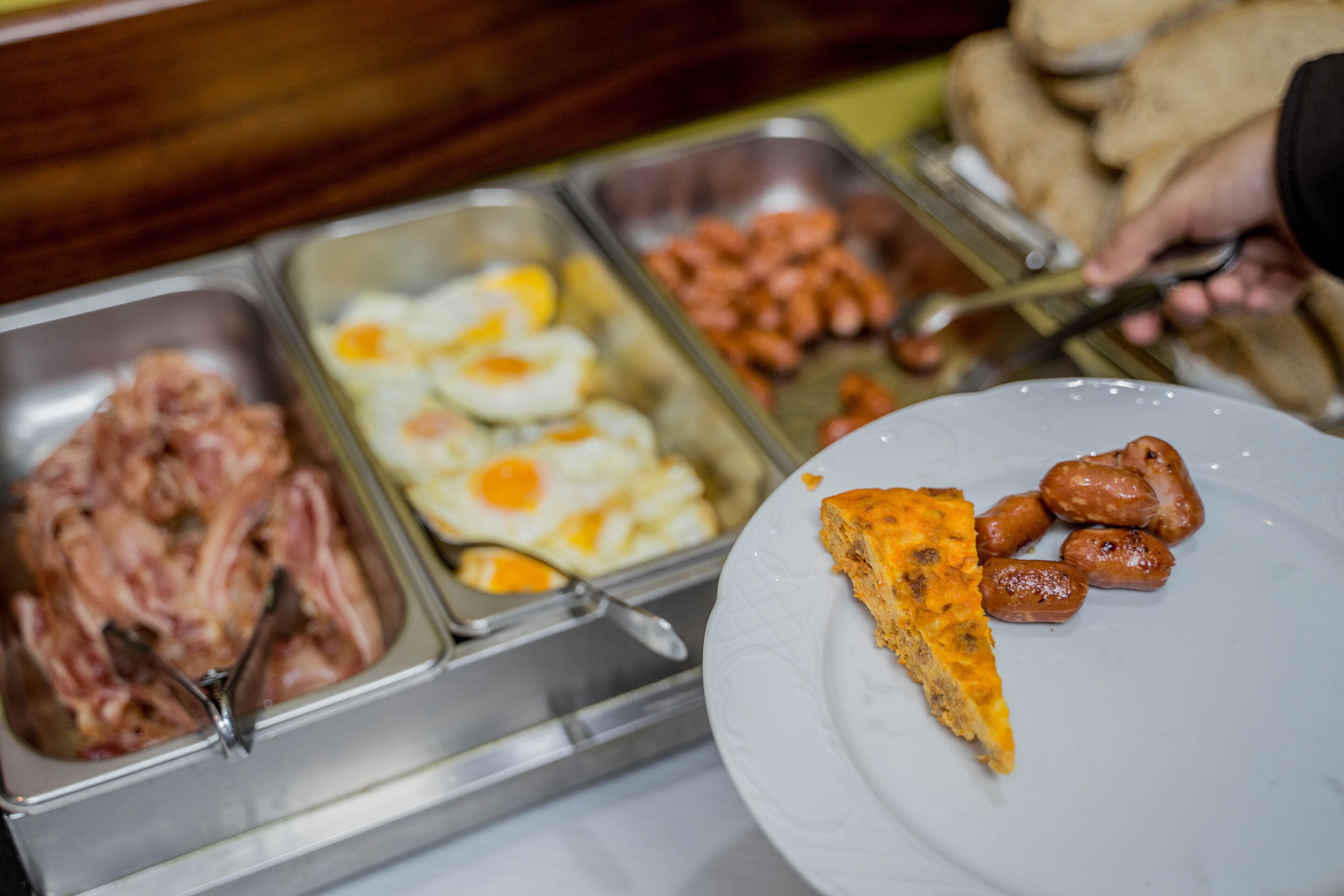 Un buffet proposant une variété de plats, notamment des viandes, des œufs et des saucisses.