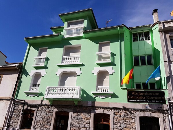A green building with balconies and a sign for 'Alojamientos Calzada Romana'. - Alojamiento Calzada Romana (Belmonte de Miranda)
