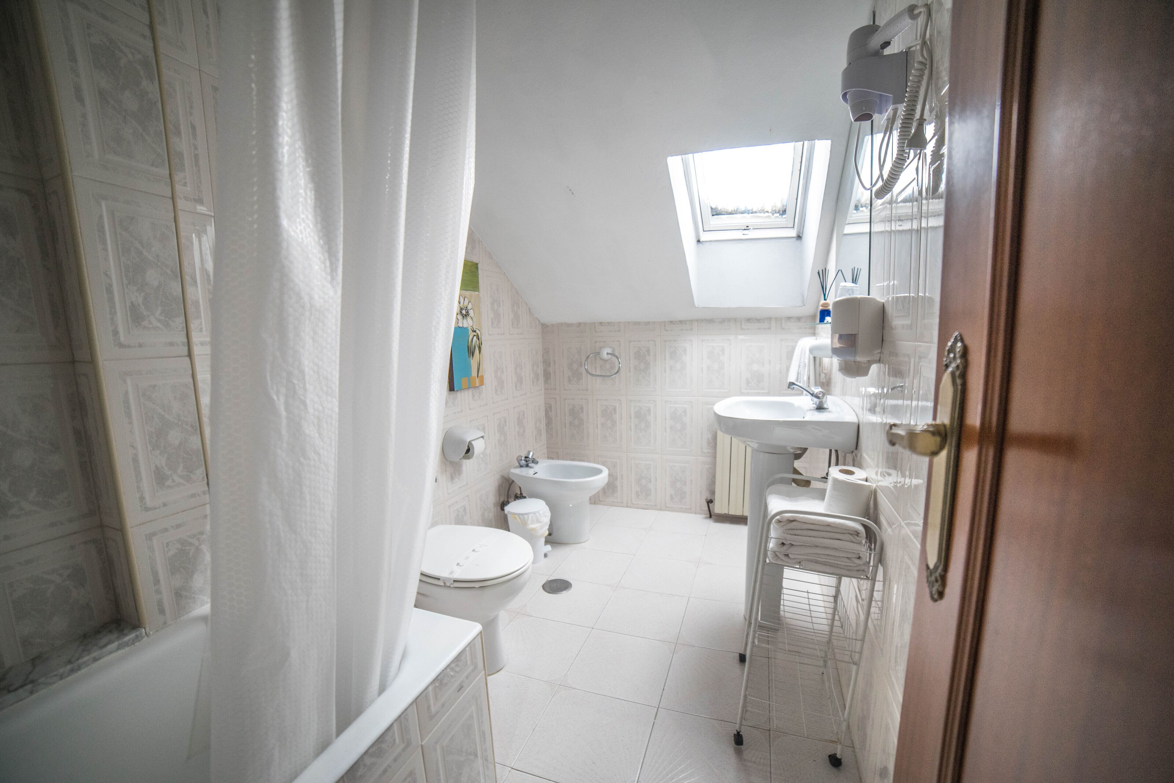 Un baño con inodoro, bidé y una pequeña ventana.