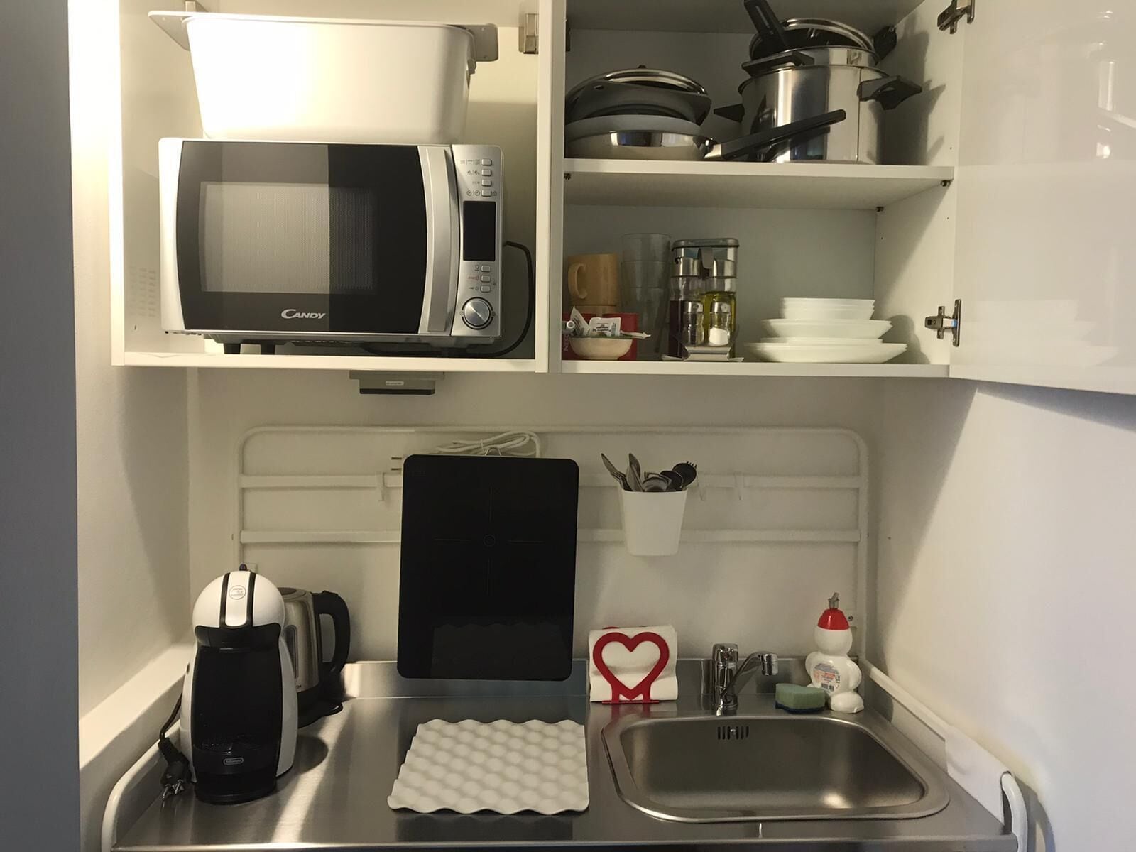 Een kleine keuken met een magnetron, koffiezetapparaat en een spoelbak.