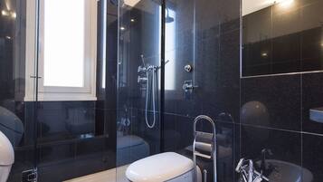 A modern bathroom with a glass-enclosed shower, a white toilet, and a sink with a chrome faucet.