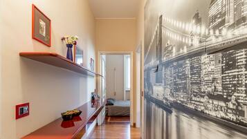 Ein Flur mit einer Holzbank, einem Blumenstrauß in einer Vase und einem gerahmten Bild an der Wand.