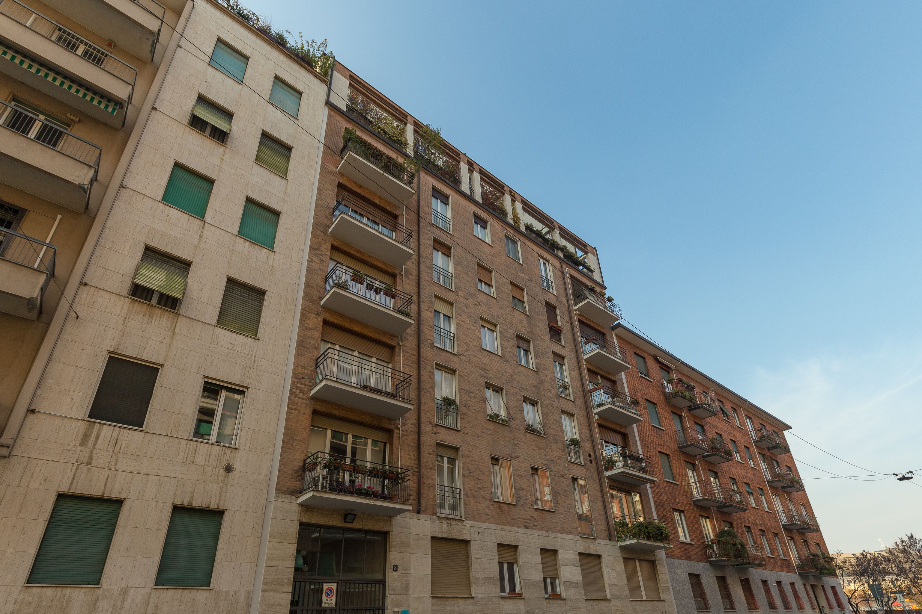 Un edificio residencial de varios pisos con balcones, ventanas y cielo despejado.