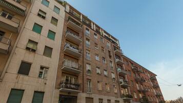 Un edificio residencial de varios pisos con balcones, ventanas y cielo despejado.