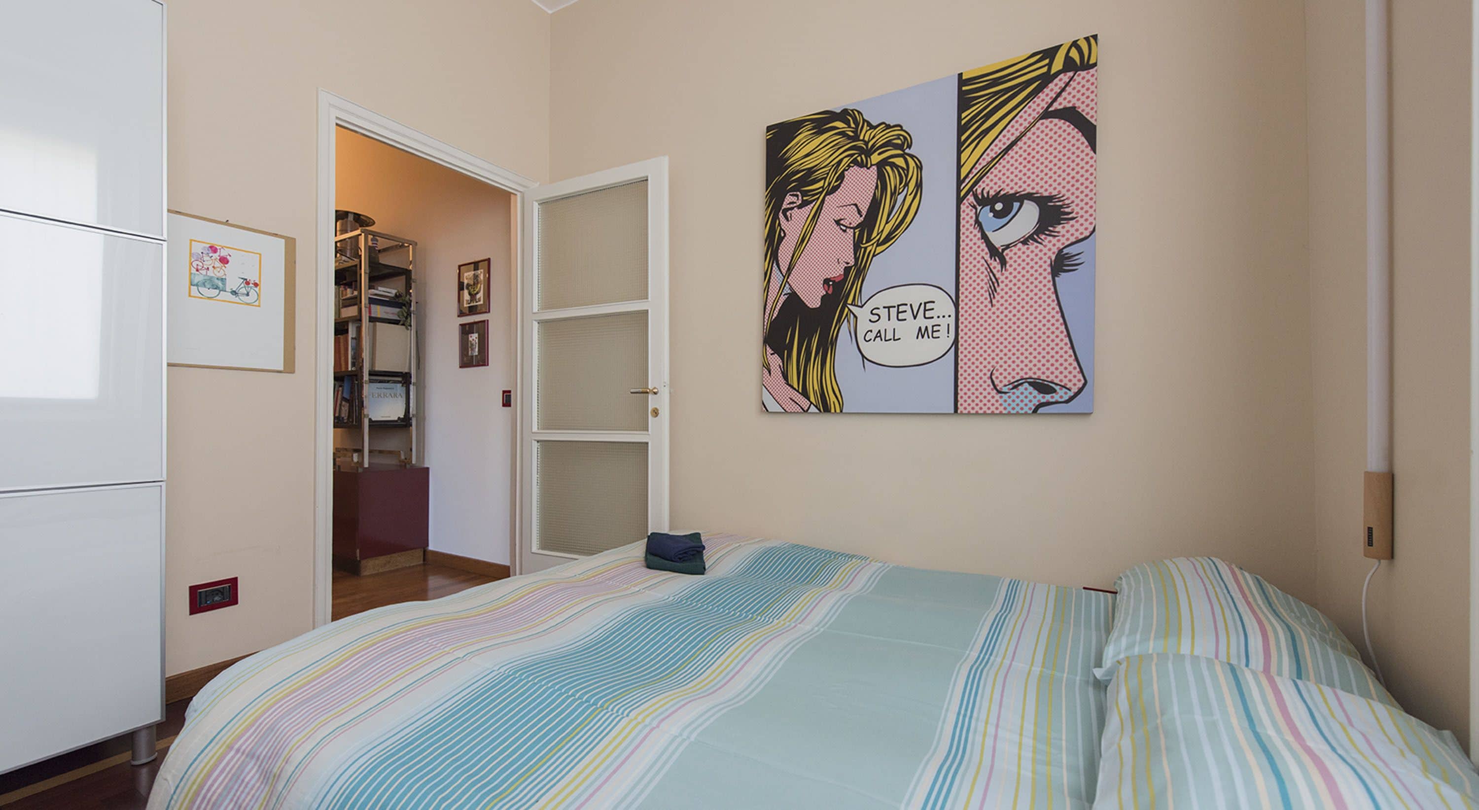 A bedroom with a bed, a wardrobe, and a door leading to a bathroom.