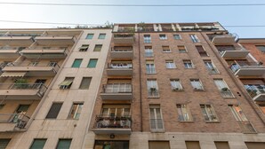 En flerlænget boligbygning med altaner, vinduer og en murstensfacade.