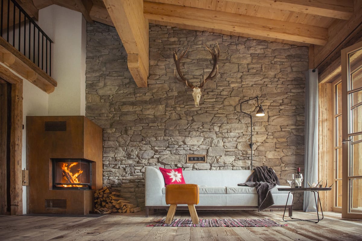 Une pièce chaleureuse avec un mur en pierre, une cheminée, un canapé et un plafond en bois.