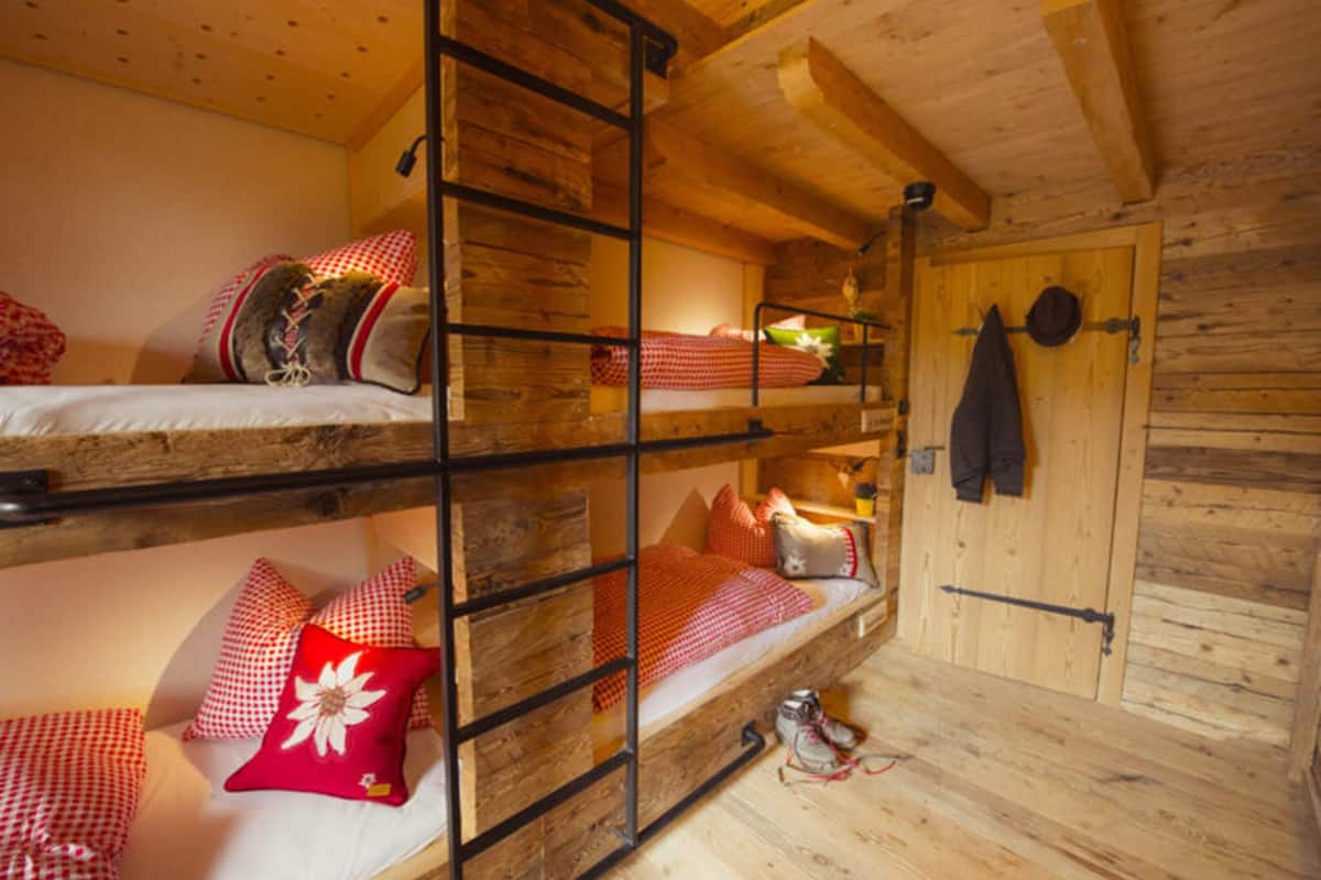 Une chambre avec un lit superposé, des murs en bois et une porte.
