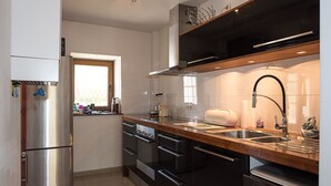 Una cocina moderna con electrodomésticos de acero inoxidable, encimera de madera y salpicadero negro.