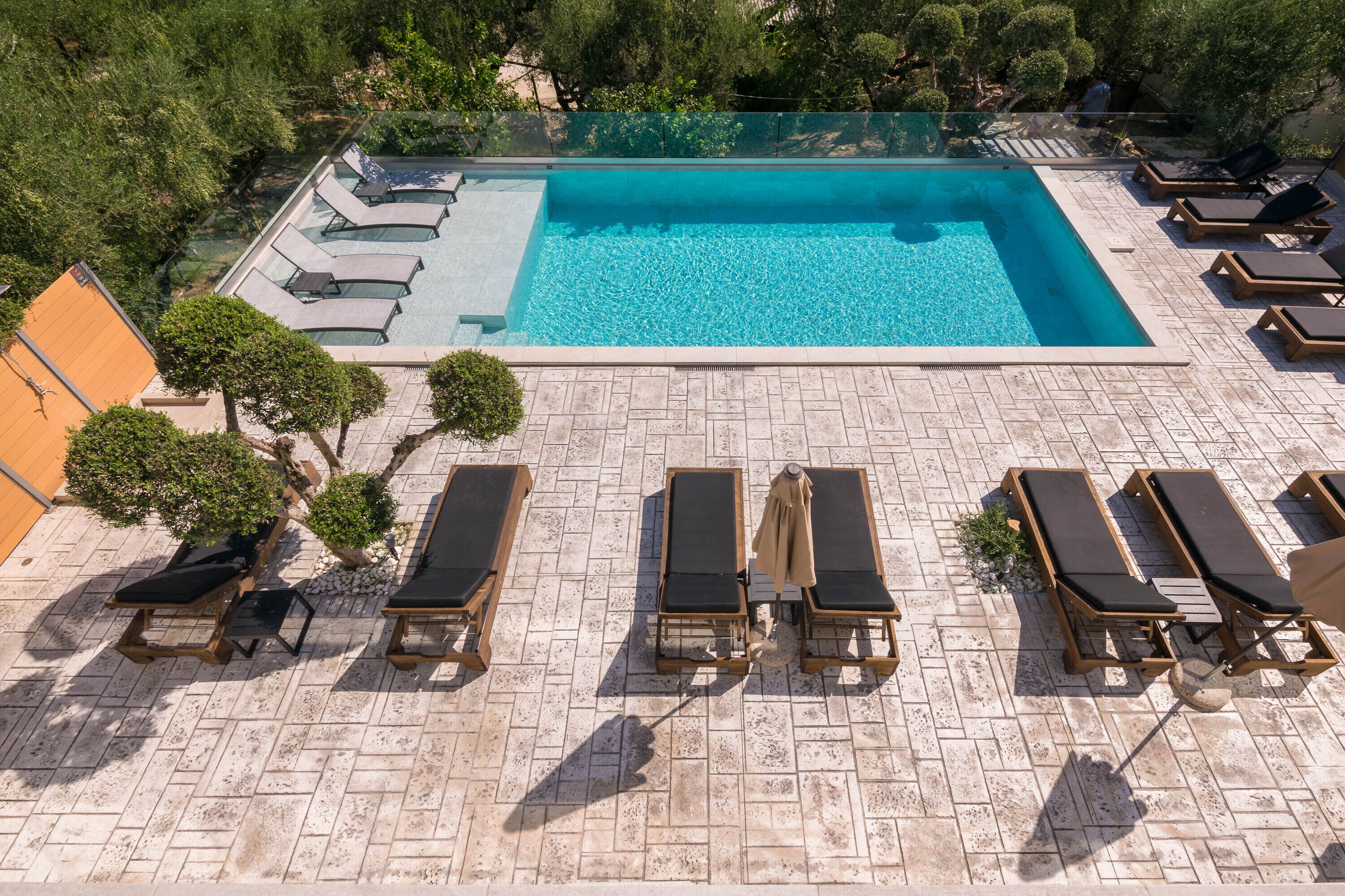 A rooftop pool with clear blue water, surrounded by lounge chairs and a tiled deck.
