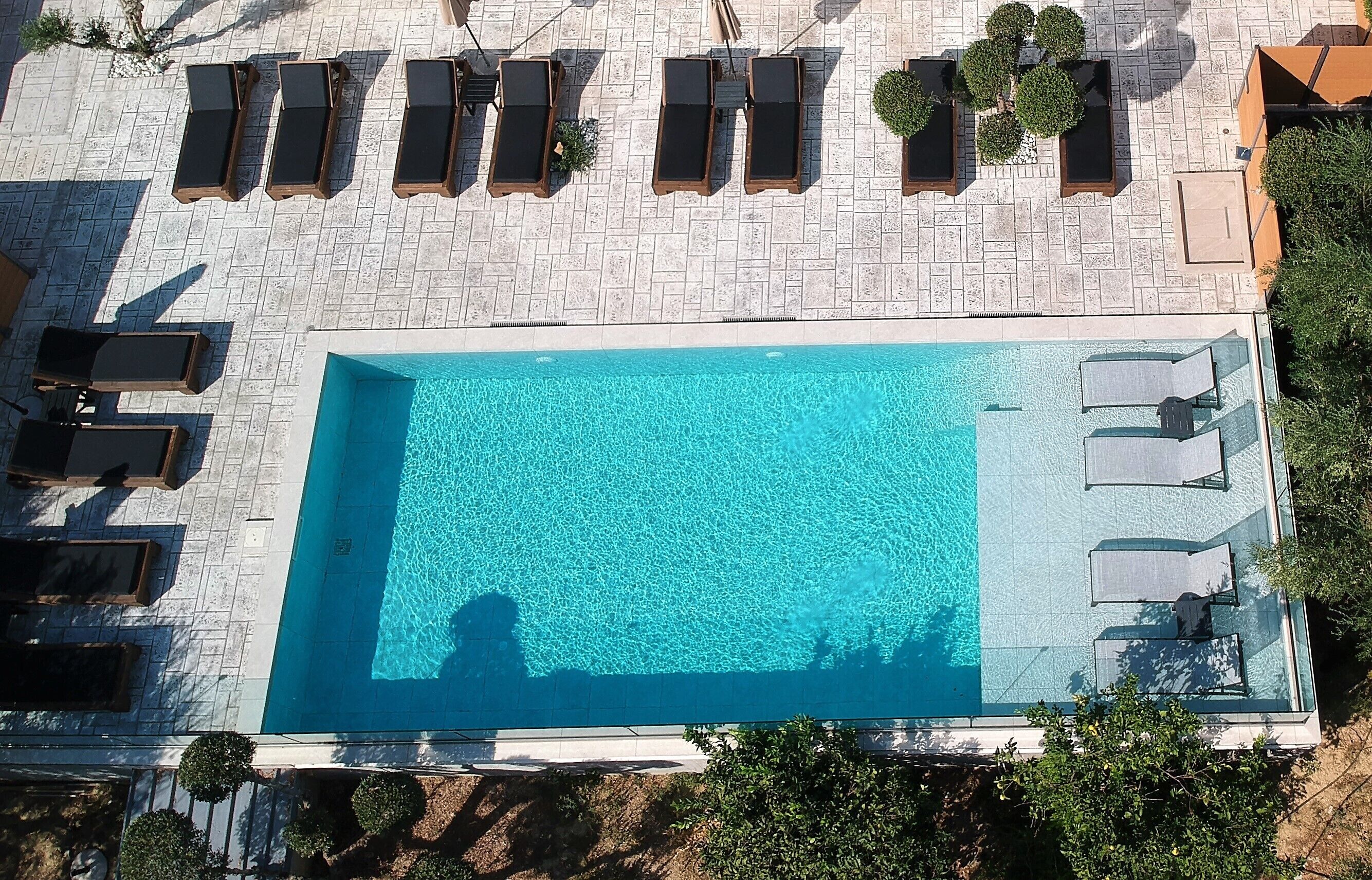An aerial view of a rectangular swimming pool with lounge chairs arranged around its perimeter.