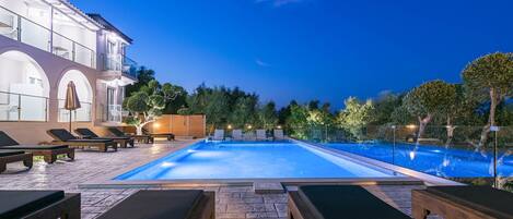 A swimming pool with lounge chairs and a building with balconies.