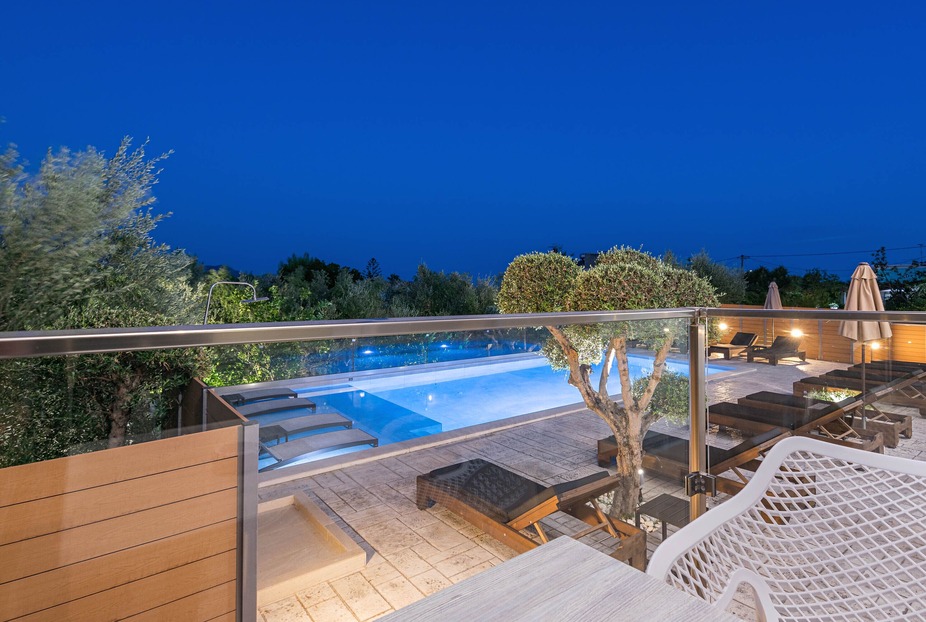 An outdoor pool area with lounge chairs and a glass balustrade.