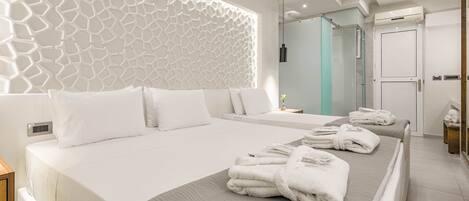 Une chambre d’hôtel moderne dotée d’un grand lit, d’un mur décoratif, d’une salle de bain avec une douche en verre et d’une porte intégrant un appareil de climatisation.