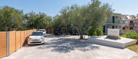 A residential area with parked cars, a sign for 'Litore Luxury Living', and a concrete driveway.