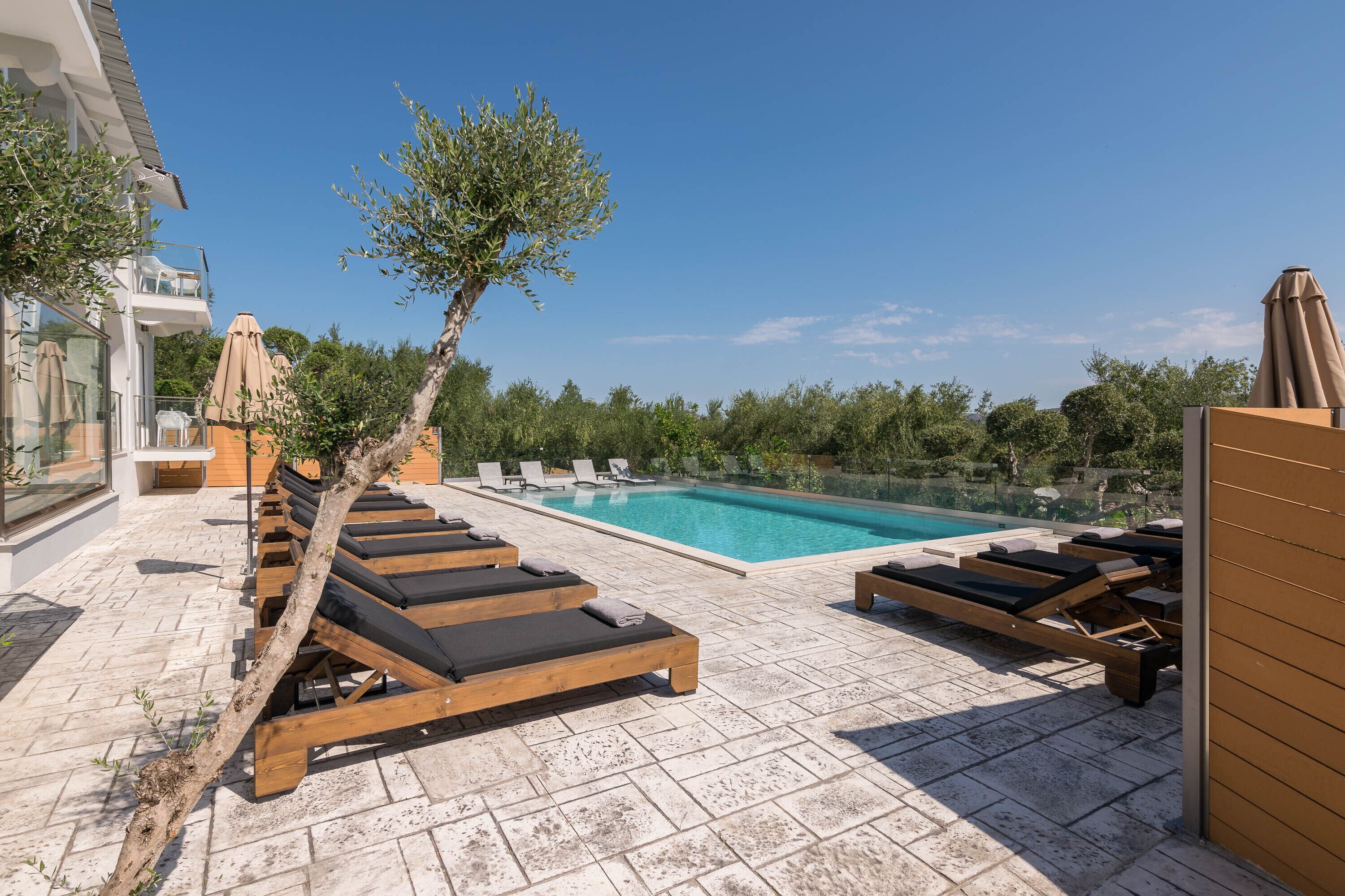 A rooftop pool area with lounge chairs and a clear blue sky.