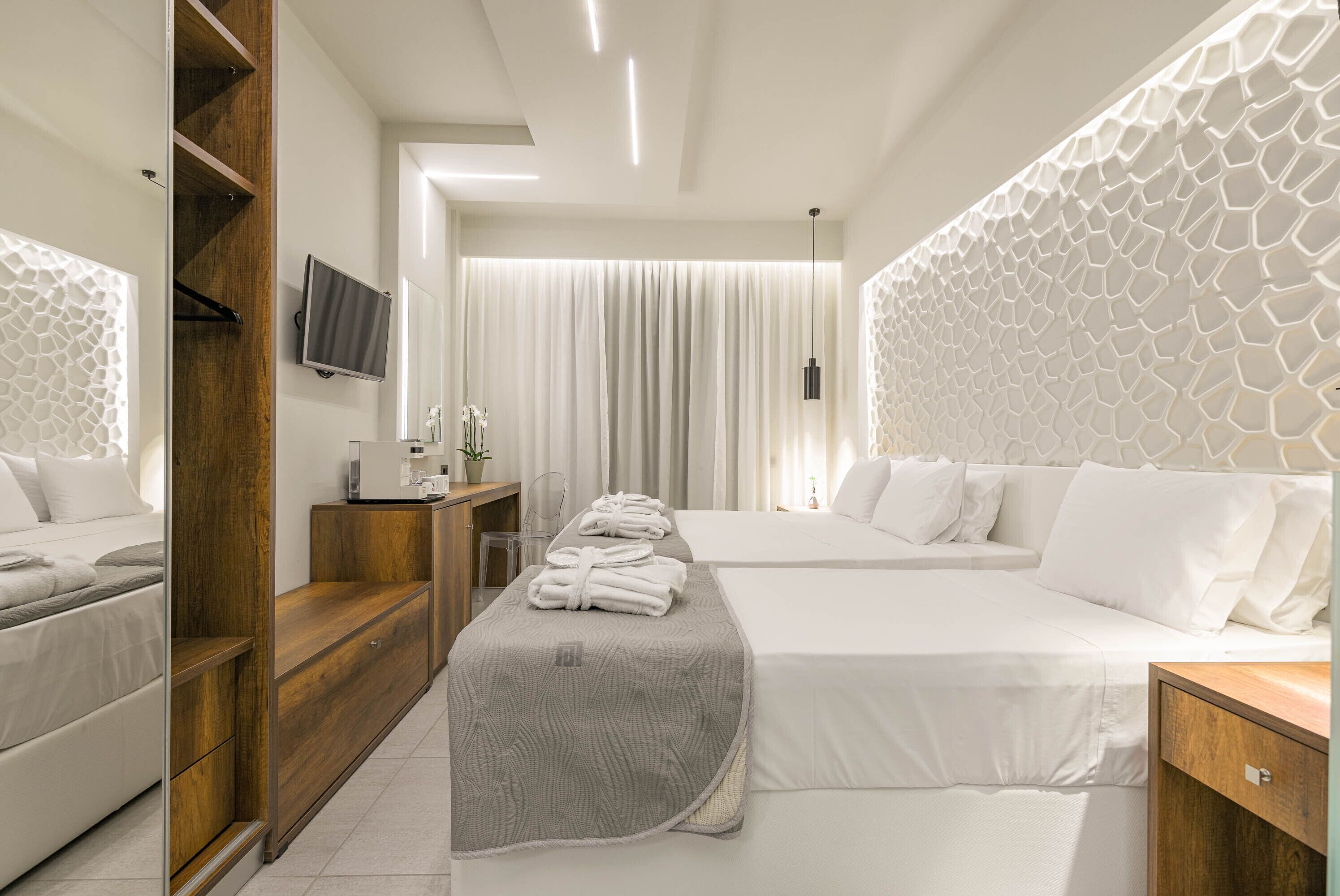 A modern hotel room with two beds, a wooden wardrobe, a TV, and a large window with curtains.