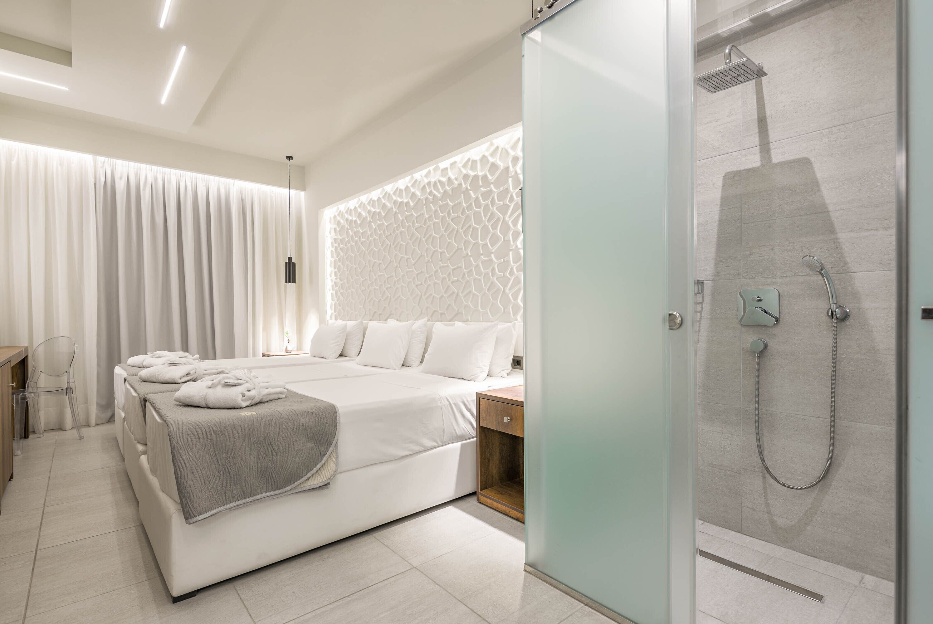 A modern bedroom with a large bed, a bedside table, a nightstand, a shower area, and a glass door leading to the shower.