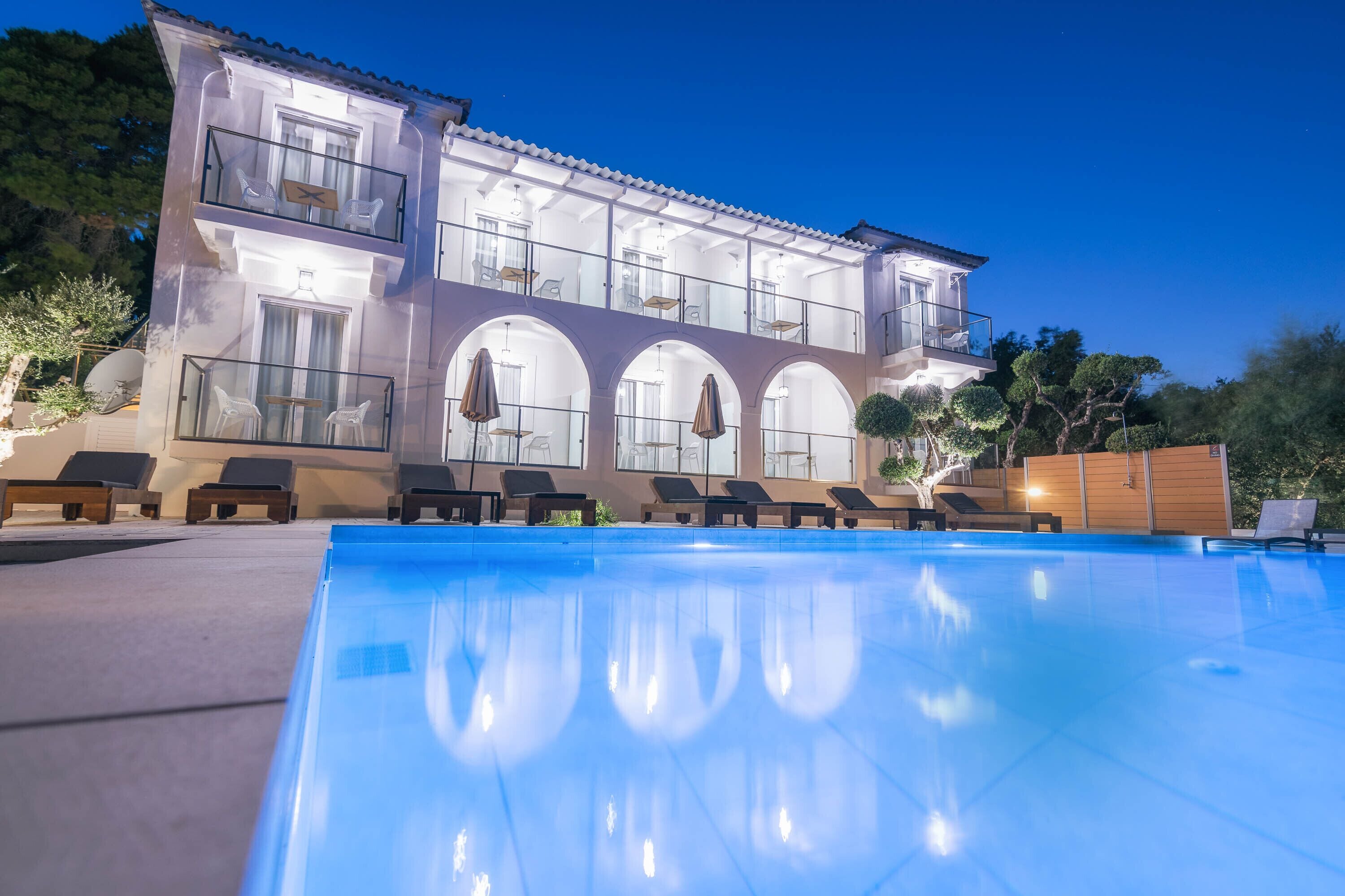 Un edificio de dos plantas con piscina, mobiliario exterior y balcón.